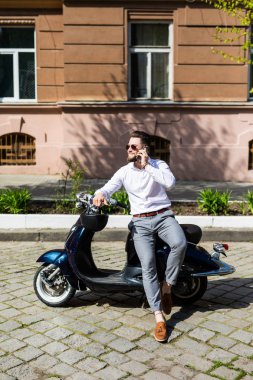 Şehir telefonda konuşurken sokak motosiklet üzerinde oturan yakışıklı adam