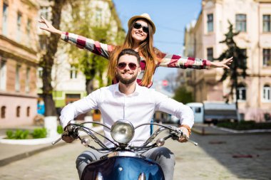 Güzel genç çift sürme scooter mutlu kadın uzanmış silah tutmak birlikte ve gülümseyen