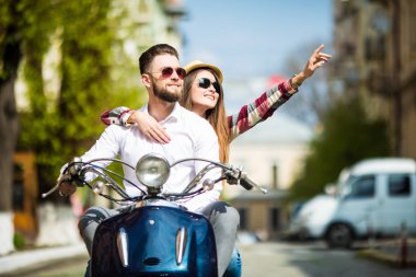 Güzel genç çift sürme scooter uzağa işaret ve gülümseyen mutlu kadın birlikte