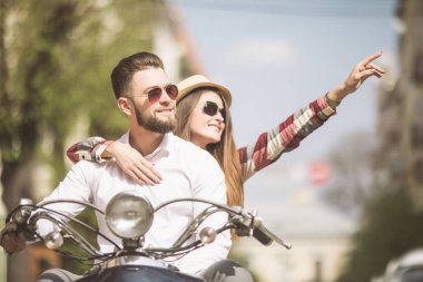 Güzel genç çift sürme scooter uzağa işaret ve gülümseyen mutlu kadın birlikte