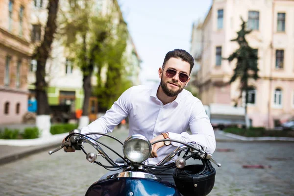 Jovem de óculos de sol montando scooter ao longo da cidade de rua — Fotografia de Stock