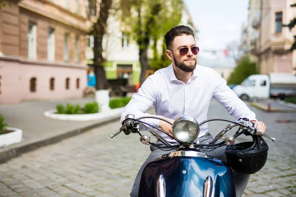 Mladý muž v jezdecké skútr podél ulice město sluneční brýle — Stock fotografie
