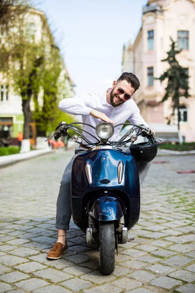 Красивый молодой человек, сидя на скутере — стоковое фото