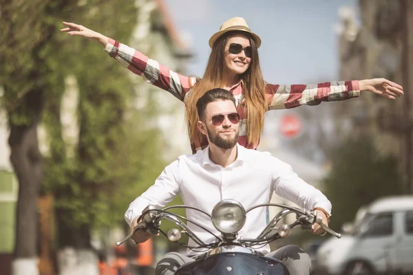 Красивая молодая пара на скутере вместе в то время как счастливая женщина поднимает руки и улыбается — стоковое фото