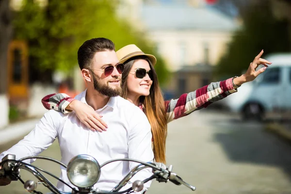 Belo jovem casal equitação scooter juntos enquanto mulher feliz apontando para longe e sorrindo — Fotografia de Stock