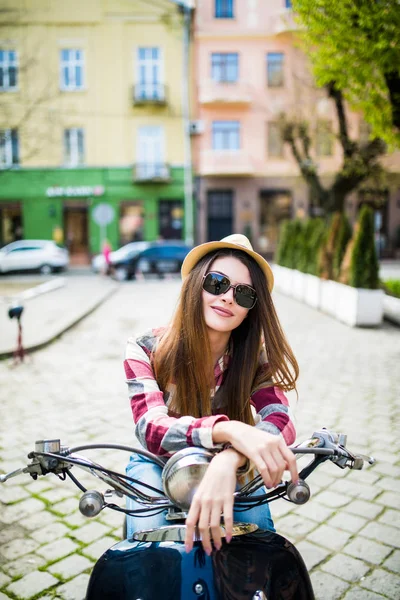 Jovem e bela mulher excitada andando de scooter ao longo da rua . — Fotografia de Stock