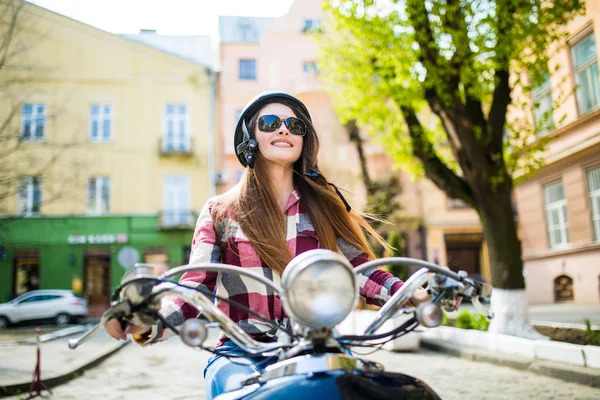 Mulher feliz atraente em uma scooter no dia de verão na rua da cidade — Fotografia de Stock