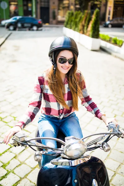 Счастливая молодая женщина едет на скутере в солнцезащитных очках и конопле на открытом воздухе, глядя в камеру — стоковое фото