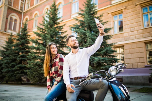 Feliz casal tomando selfie no ciclomotor na rua da cidade — Fotografia de Stock