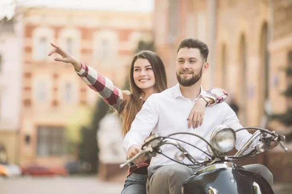 Belo jovem casal montando scooter juntos, enquanto a mulher feliz apontando para longe e sorrindo. tonificado — Fotografia de Stock