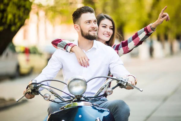 Красивая молодая пара на скутере вместе в то время как счастливая женщина указывая и улыбаясь — стоковое фото