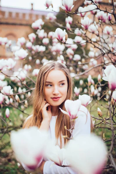 Молодая девушка отдыхает в красивом саду. Фантастическое розовое дерево магнолий — стоковое фото
