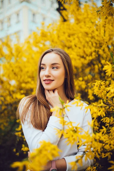 Ritratto di donna in piedi vicino all'albero giallo dei fiori in giardino . — Foto Stock