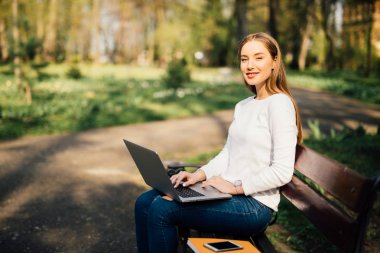 Genç kız ile bir laptop parkta bir bankta