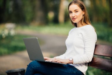 Mutlu öğrenci genç kız bir Bank Üniversitesi kampus içinde yatan bir dizüstü bilgisayar ile öğrenme
