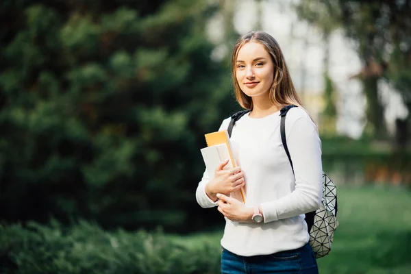 Портрет студентки с книгами в рюкзаке под открытым небом в парке улыбается счастливой возвращением в школу. Модель кавказской девушки . — стоковое фото