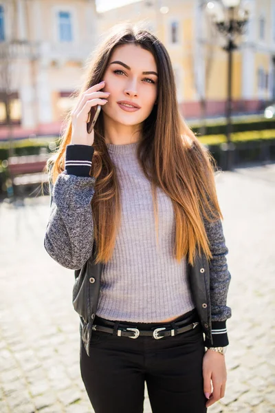 Красива молода брюнетка розмовляє на смартфоні на вулиці міста . — стокове фото