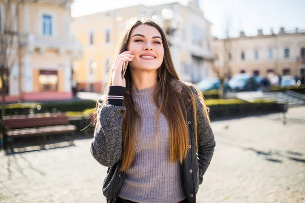 Linda jovem morena falando no telefone inteligente no fundo da rua da cidade . — Fotografia de Stock