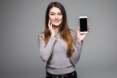 Gri arka plan üzerinde duran smartphone üzerinde gülümseyen kadın işaret.