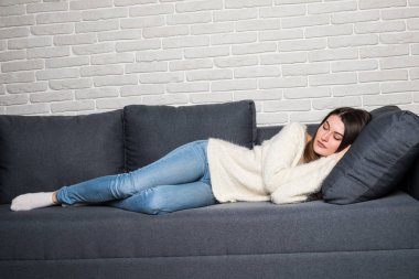 Kapalı evde kanepede uyuyan güzel genç kadın