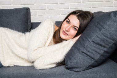 evde kanepede yatan genç gülümseyen