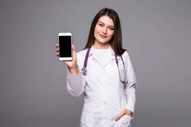 Genç kadın cep telefonu ekran gri arka plan üzerinde işaret eden doktor