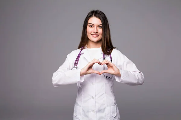 Médico médico mujer mostrando la forma del corazón gesto en gris — Foto de Stock