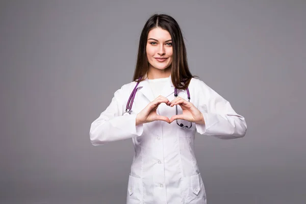 Médico médico mujer mostrando la forma del corazón gesto en gris — Foto de Stock