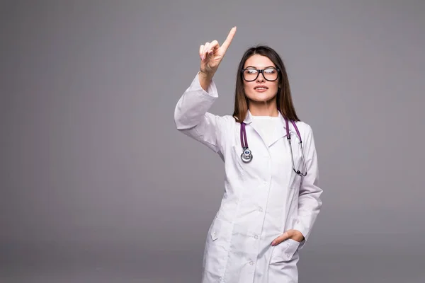 Sonriente médico feliz señalando con el dedo sobre fondo gris — Foto de Stock