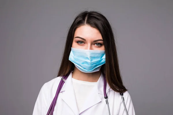 Young woman doctor or nurse in cap and face mask on grey — Stock Photo, Image