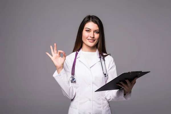 Doktor veselý krásná mladá žena s schránky zobrazeno ok znamení šedé pozadí — Stock fotografie