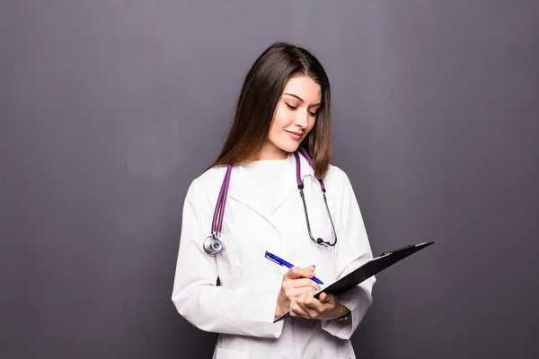 Portrét mladého lékaře s schránky na šedém pozadí — Stock fotografie