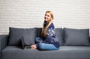 Evde oturma odasında bir dizüstü bilgisayar kullanan kadın