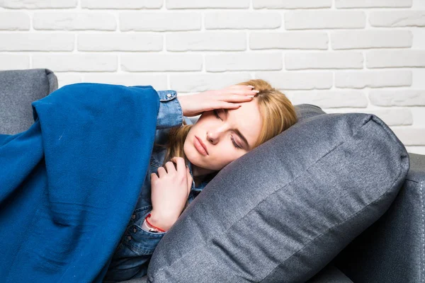 Больной молодой женщины дремлет на диване, обнимается с одеялом и — стоковое фото