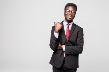 Yakışıklı Afrika delikanlı uzağa işaret ve gri arka plan karşı dururken gülümseyen resmi kıyafeti