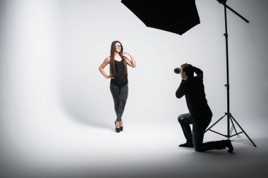 Profesyonel fotoğraf stüdyoda çekim. Güzel genç model gülümseyen ve poz. fotoğrafçı bir dijital kamera ile fotoğraf çekmek