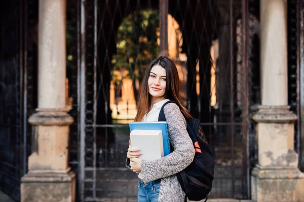 Estudante feminina ao ar livre segurando um caderno e sorrindo perto de Uni — Fotografia de Stock