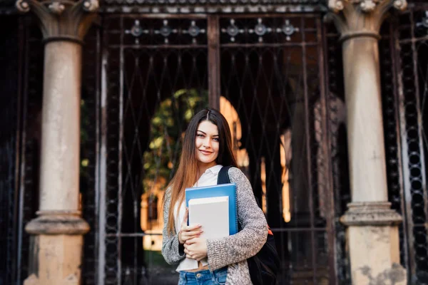 Estudante feminina ao ar livre segurando um caderno e sorrindo perto de Uni — Fotografia de Stock