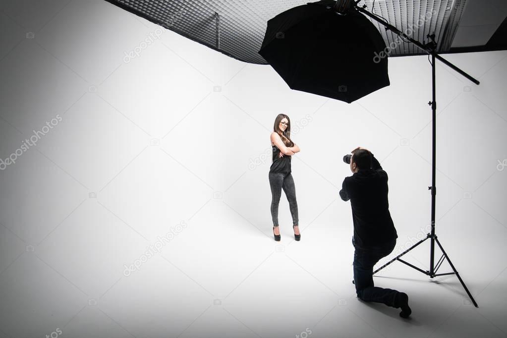 Girl the photographer takes pictures of model in black on a white background