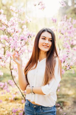 Açık çiçekli Manolya ağacı yakınındaki güzel bir genç kadının portresi.