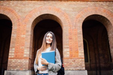 Sırt çantası ve ayakta ve parkta gülümsüyor not defterleri neşeli çekici genç kadın