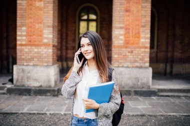 Üniversite kampüsünde telefon muhteşem mutlu öğrenci holding dizüstü konuşmak