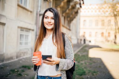 Sokak kahve içme ve cep telefonu açık havada kullanarak duran genç kadın
