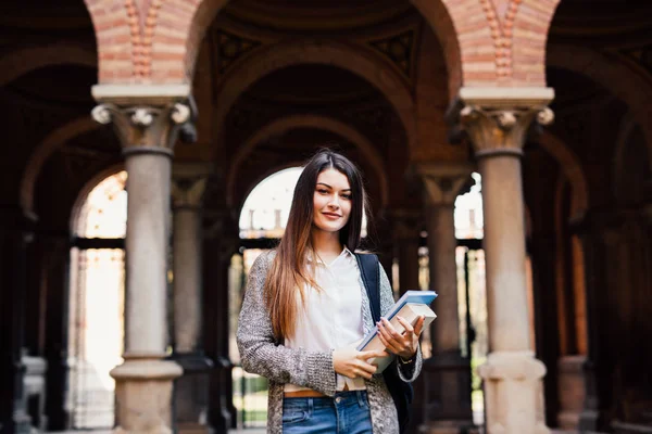 Estudante sorridente com livros ao ar livre perto da Universidade — Fotografia de Stock