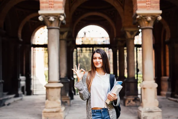 Retrato de uma estudante sorridente mostrando tudo bem ao ar livre perto da Universidade — Fotografia de Stock