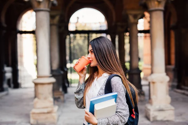 Joven estudiante de belleza con cuadernos al aire libre la universidad beber una taza de café — Foto de Stock