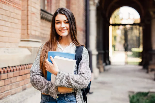 Красивая студентка улыбается перед камерой на кампусе университета — стоковое фото