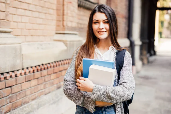 Улыбающаяся студентка в черных очках с папками и сумкой сзади — стоковое фото