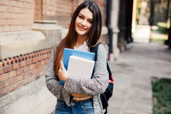 Sorridente estudante do sexo feminino em óculos pretos com pastas e saco nas costas — Fotografia de Stock