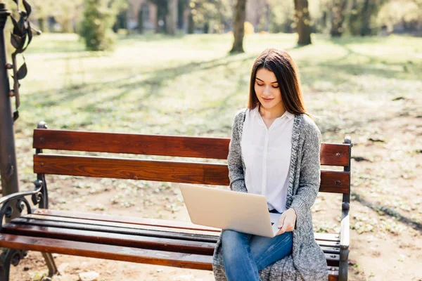 Молодая женщина с ноутбуком на скамейке в парке солнечный день — стоковое фото